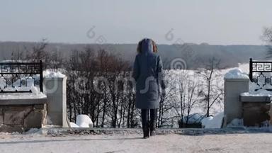 在冬天的城市公园里，穿着蓝色<strong>羽绒服</strong>和带皮帽下楼梯的女子面目全非